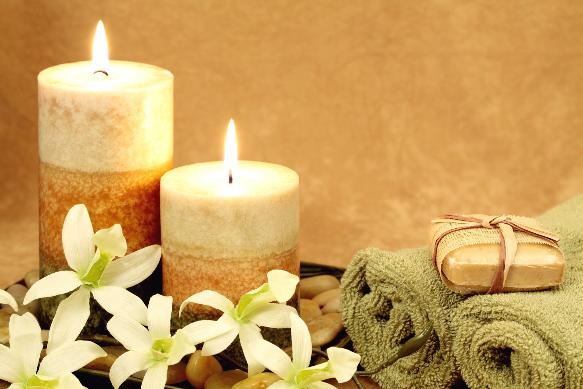 Warm candles glowing beside white florals — the scent and light that welcome each guest